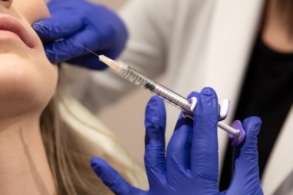 A provider at Spa 29 wearing purple medical gloves and getting ready to inject a blonde female patient with dermal filler near Brunswick, GA.